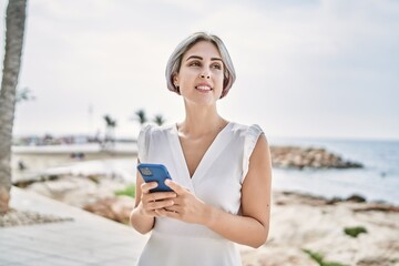 Sticker - Young caucasian girl smiling happy using smartphone at the beach.