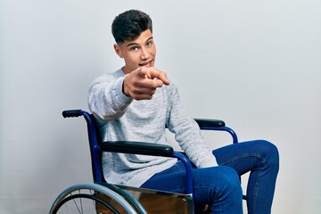 Wall Mural - Young hispanic man sitting on wheelchair pointing displeased and frustrated to the camera, angry and furious with you