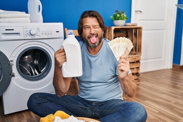 Sticker - Handsome middle age man saving money of laundry detergent sticking tongue out happy with funny expression.