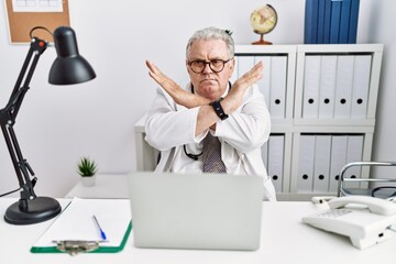 Sticker - Senior caucasian man wearing doctor uniform and stethoscope at the clinic rejection expression crossing arms doing negative sign, angry face