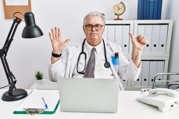 Canvas Print - Senior caucasian man wearing doctor uniform and stethoscope at the clinic showing and pointing up with fingers number six while smiling confident and happy.