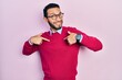 Hispanic man with beard wearing business shirt and glasses looking confident with smile on face, pointing oneself with fingers proud and happy.