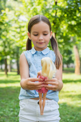 Wall Mural - pleased girl in sleeveless blouse playing with doll in park.