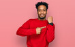© Krakenimages.com - Young african american man with beard wearing casual winter sweater in hurry pointing to watch time, impatience, looking at the camera with relaxed expression