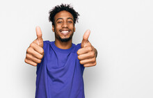 Young African American Man With Beard Wearing Casual Purple T Shirt Approving Doing Positive Gesture With Hand, Thumbs Up Smiling And Happy For Success. Winner Gesture.