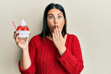 Canvas Print - Beautiful brunette woman eating strawberry ice cream covering mouth with hand, shocked and afraid for mistake. surprised expression