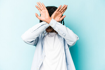 Young African American man isolated on blue background keeping two arms crossed, denial concept.