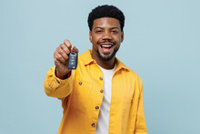 Young Smiling Happy Fun Man Of African American Ethnicity 20s Wear Yellow Shirt Hold Giving Car Keys Fob Keyless System Isolated On Plain Pastel Light Blue Background Studio. People Lifestyle Concept