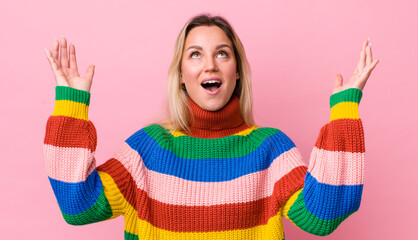 Wall Mural - pretty blonde woman feeling happy, amazed, lucky and surprised, celebrating victory with both hands up in the air