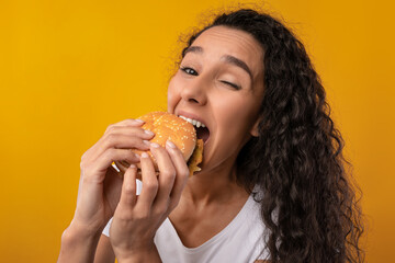 Wall Mural - Funny Latin Lady Holding Burger Biting Sandwich At Studio