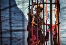 A Skeleton In A Hanging Cage Wearing Rags