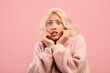 © Prostock-studio - Young caucasian woman feeling scared, touching cheeks with hands, posing on pink studio background
