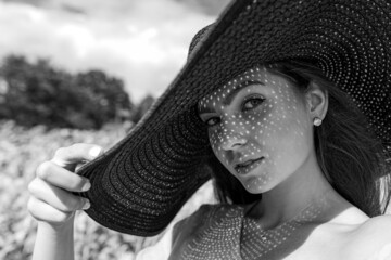 monochrome portrait of beautiful woman in elegant hat, pattern of shadows falling on her face