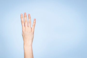 Wall Mural - Female hand shows number four. Woman hand showing four fingers, pointing fingers up on light blue background