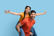 © Prostock-studio - Cheerful Arab Couple Having Fun Together Over Blue Studio Background