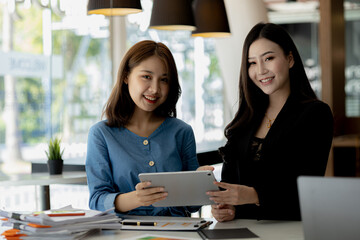 Atmosphere in the office of a startup company, two female employees are discussing, brainstorming ideas to working on summaries and marketing plans to increase sales and prepare reports to managers.