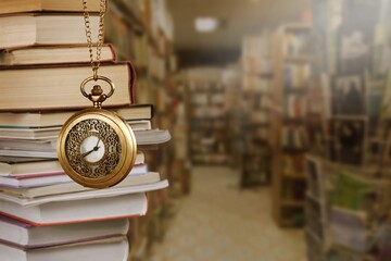 Wall Mural - old clock on a chain with stack books on library background. retro clock as a symbol of time a books