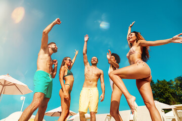 Group of friends in swimsuit dance music in a swimming pool