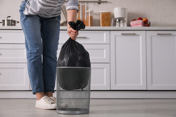 Woman taking garbage bag out of bin at home, closeup