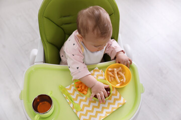 Sticker - Cute little baby eating food in high chair indoors, top view