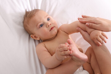 Poster - Mother massaging her cute baby with oil on bed, closeup