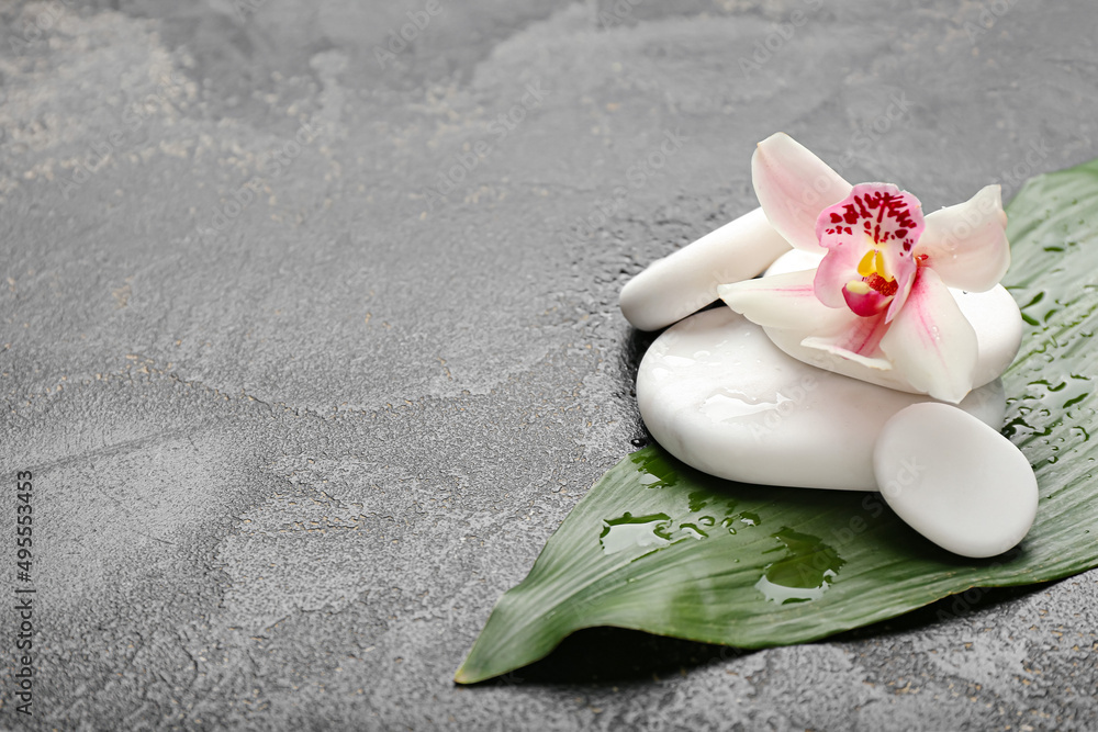 Spa stones with orchid flower and tropical leaf on dark background