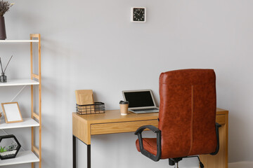 Canvas Print - Modern workplace with laptop and cup of coffee near light wall in office