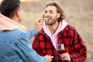 Canvas Print - Happy gay couple having picnic outdoors on autumn day