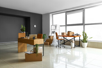 Wall Mural - Cardboard boxes with belongings and furniture in interior of office on moving day