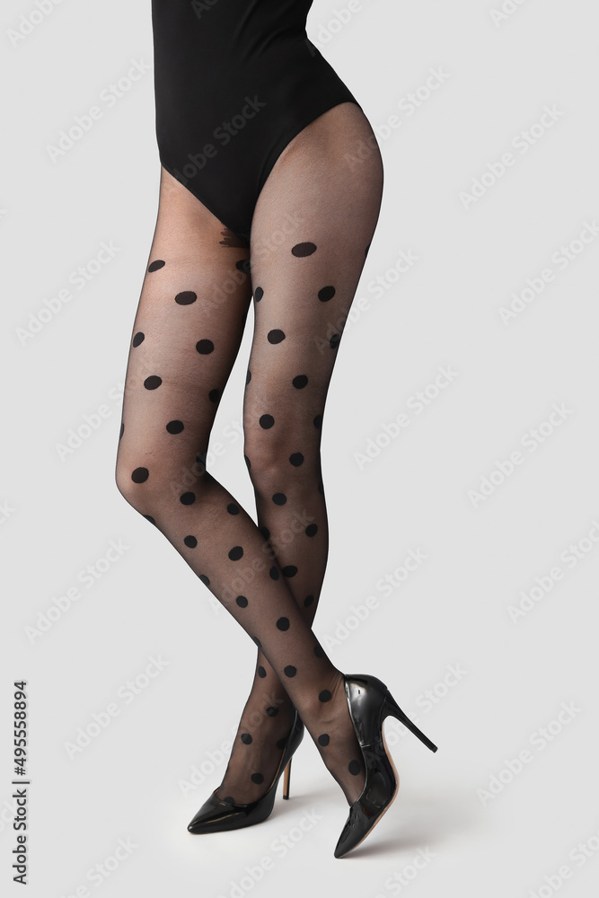Beautiful young woman in black tights on light background