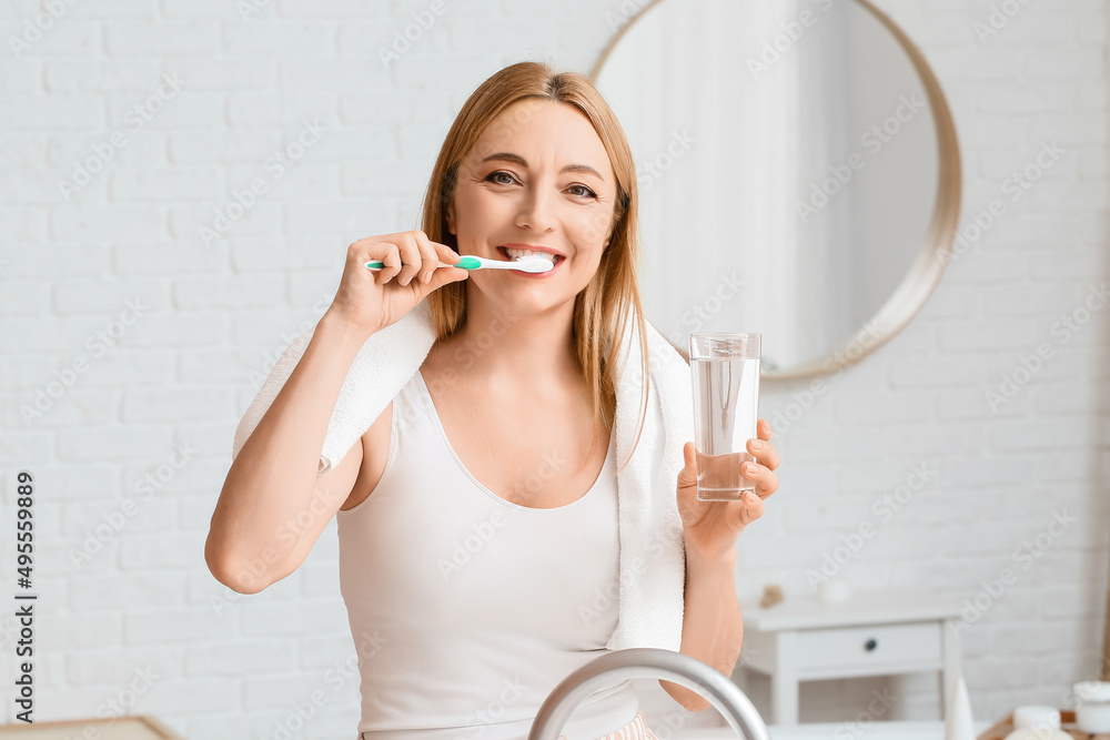 Beautiful mature woman  brushing teeth in bathroom