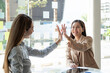 © Natee Meepian - Asian businesswoman giving high five to colleague in meeting. Happy business professionals having meeting in office conference room.