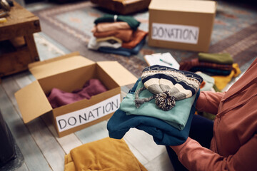 Wall Mural - Close up of woman packing warm clothes in donation boxes for charitable foundation.