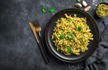 Wall Mural - Fusilli pasta and basil pesto sauce on a black background.