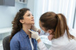 © Graphicroyalty - medicine, healthcare and medical exam concept - doctor or nurse checking patient's tonsils at hospital. Endocrinologist examining throat of young woman in clinic