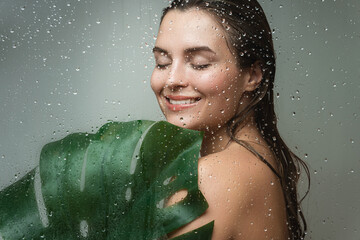 Wall Mural - young woman with a smooth skin holding monstera deliciosa plant leaf