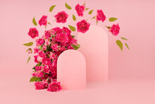 Spring Fresh Pink Roses As Arch With Two Empty Rounded Doors As Podiums Mockup With Fly Green Leaves, Buds As Swirl For Presentation Cosmetic Products, Goods, Advertising, Design On Pink Background.