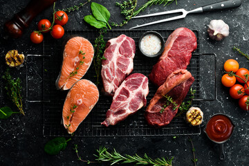 Wall Mural - A set of different meats: fish, beef and pork. Source of animal protein for the body. On a black stone background.
