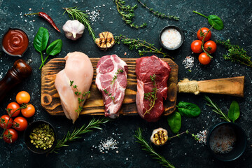 Wall Mural - Meat: beef steak, chicken breast and pork. Ready to cook. Top view. On a black stone background.