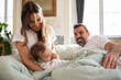 © KAMPUS - Cheerful woman playing with her baby son in bed. Happy parents lying in bed with child in morning. Family at home concept