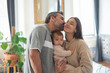 © KAMPUS - Portrait of happy mid adult Caucasian family with little child standing together at home. Woman holding baby son and man kissing his wife. Family at home concept