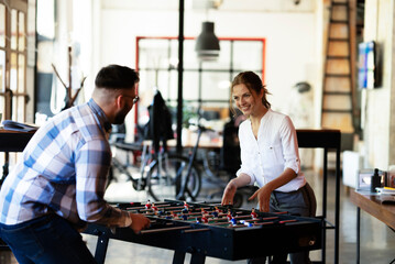 Colleagues having fun at work. Businessman and businesswoman playing table soccer.