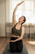 © Andrii - Young female does indoor yoga exercises stretching her body at home