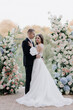  Beautiful bride and groom in the zone of the wedding ceremony of fresh white and pink flowers. Design and organization of outdoor celebrations.