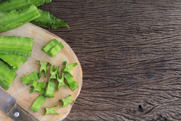 Close up of Winged bean or Psophocarpus tetragonolobus on a wooden cutting board on the wooden table. empty space for text.