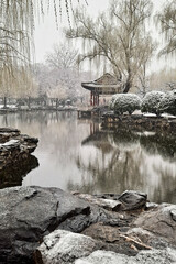 Sticker - Chinese pavilion surrounded by pond and trees on snowy day, Beijing China.