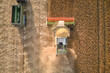 Aerial view of combine harvester and cargo trailer working during harvesting season on large ripe wheat field. Agriculture and transportation of raw grain concept
