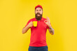 © be free - Happy winking guy in casual red cap and tshirt giving OK holding cup yellow background, coffee