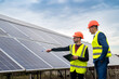 © RomanR - two young workers in overalls and helmets check the installed solar panels.