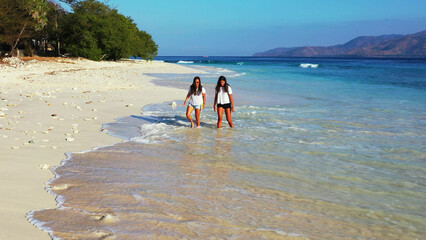 Poster - Young girls walk along the beach in the evening while relaxing at a tropical resort.